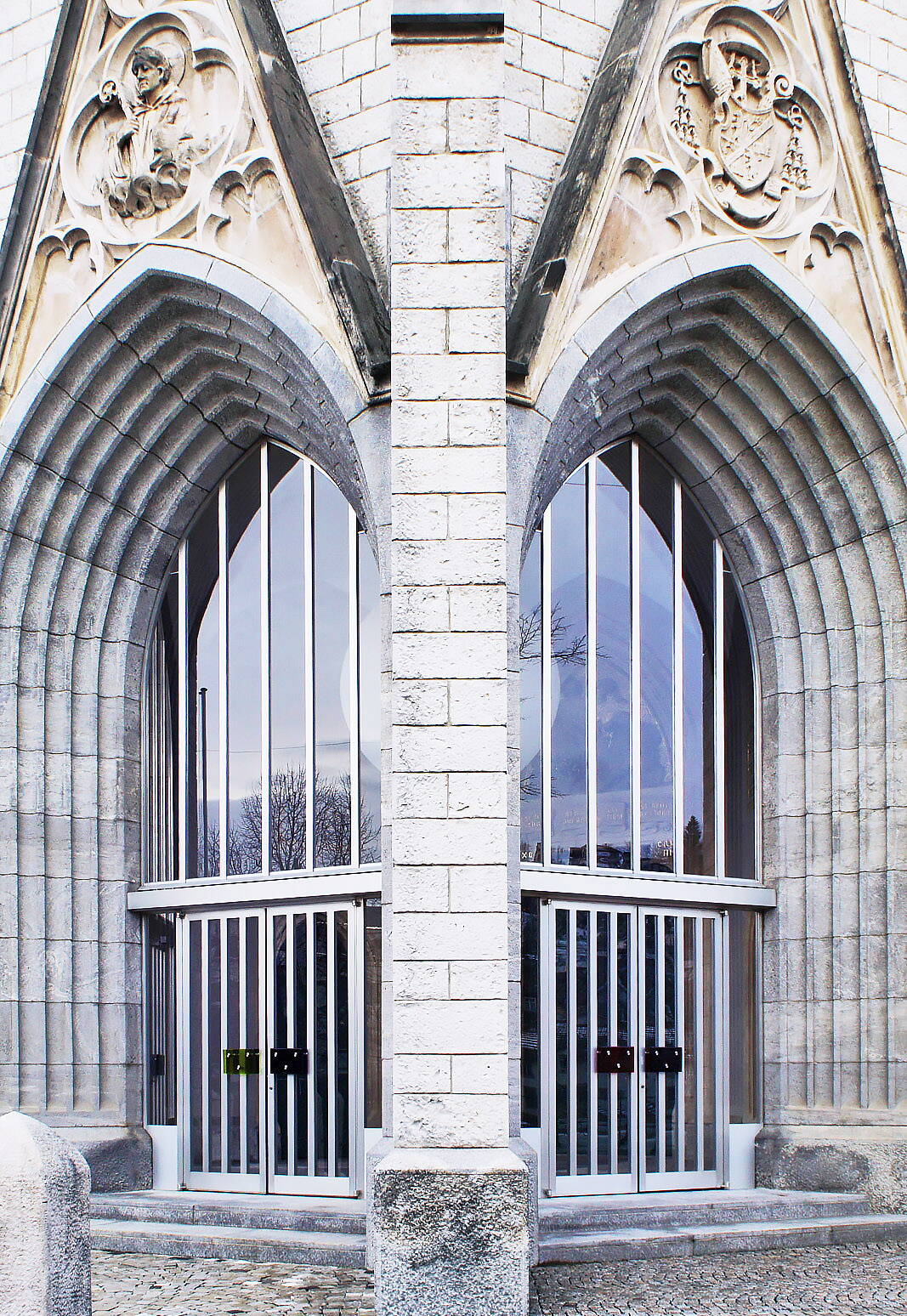 Sicht auf die zwei grossen, spitzzulaufenden Fenster einer Kirche.