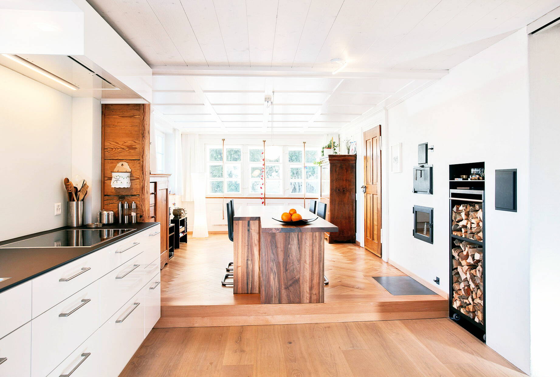 Schlichte, moderne Küche in Holz gearbeitet im Dachstock eines Altbaus mit grosszügigem Fenster.
