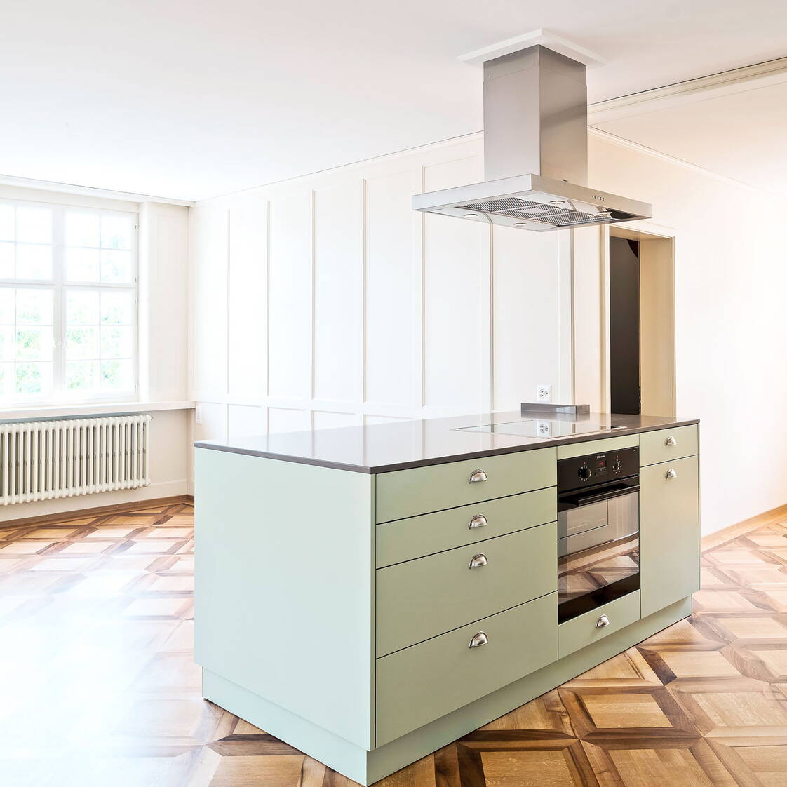 Moderne, offene Küche in einem ehemaligen Altbauwohnzimmer mit schönem Holzparkett.