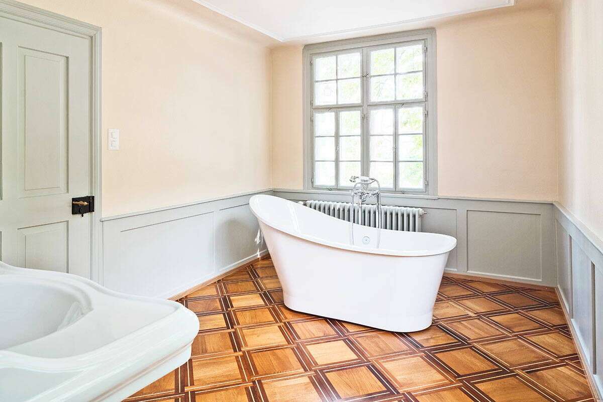 Sicht in ein frisch renoviertes Altbaubadezimmer mit freistehender Badewanne und schönen Holzböden.