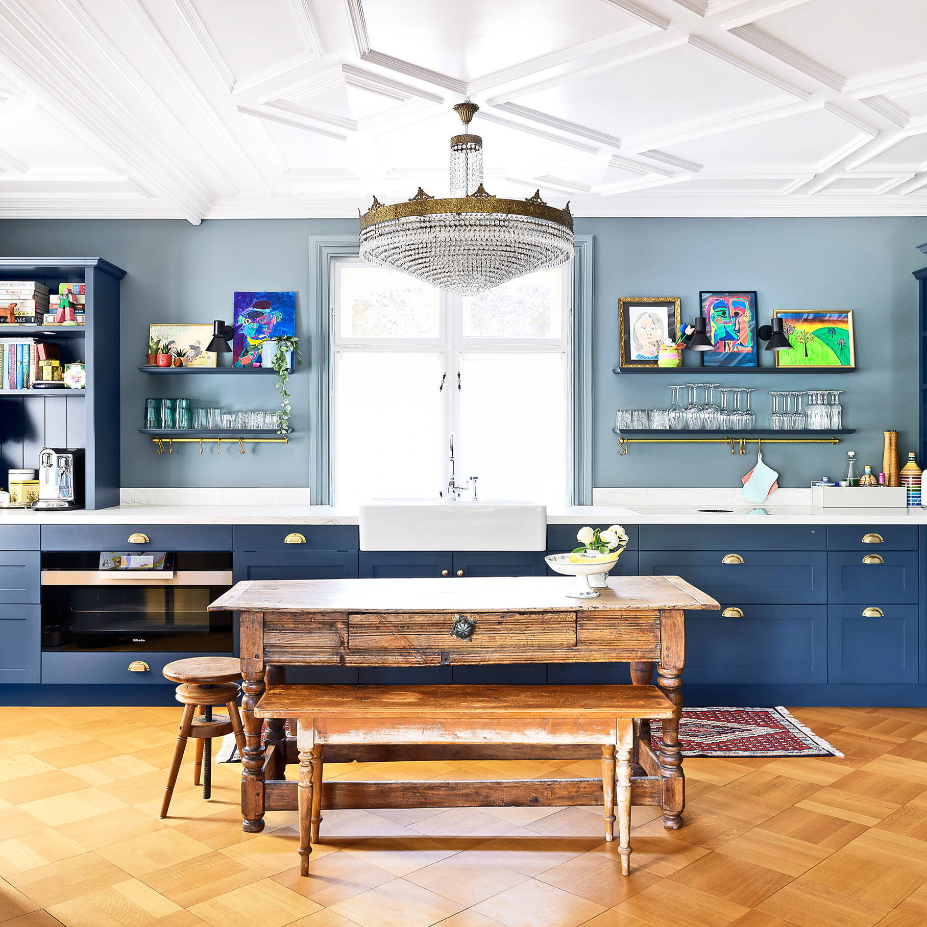 Eine modern umgebaute Küche mit Altbaucharme, Oberflächen und Boden in Holz gearbeitet, Stuckaturen und Kronleuchter an der Decke.