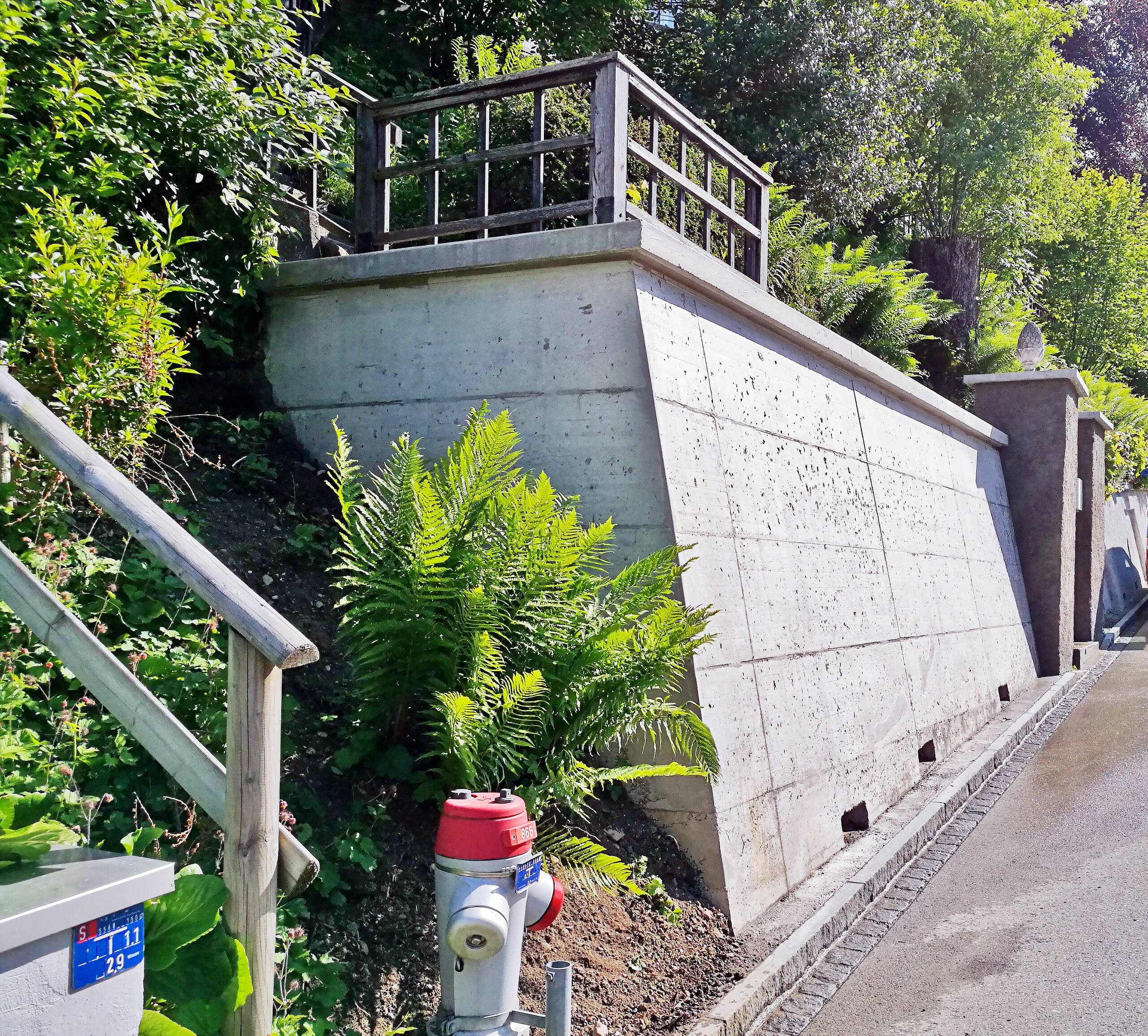 Betonmauer am Strassenrand der Berneggstrasse in St.Gallen mit Begrünung vor und hinter dem Objekt.